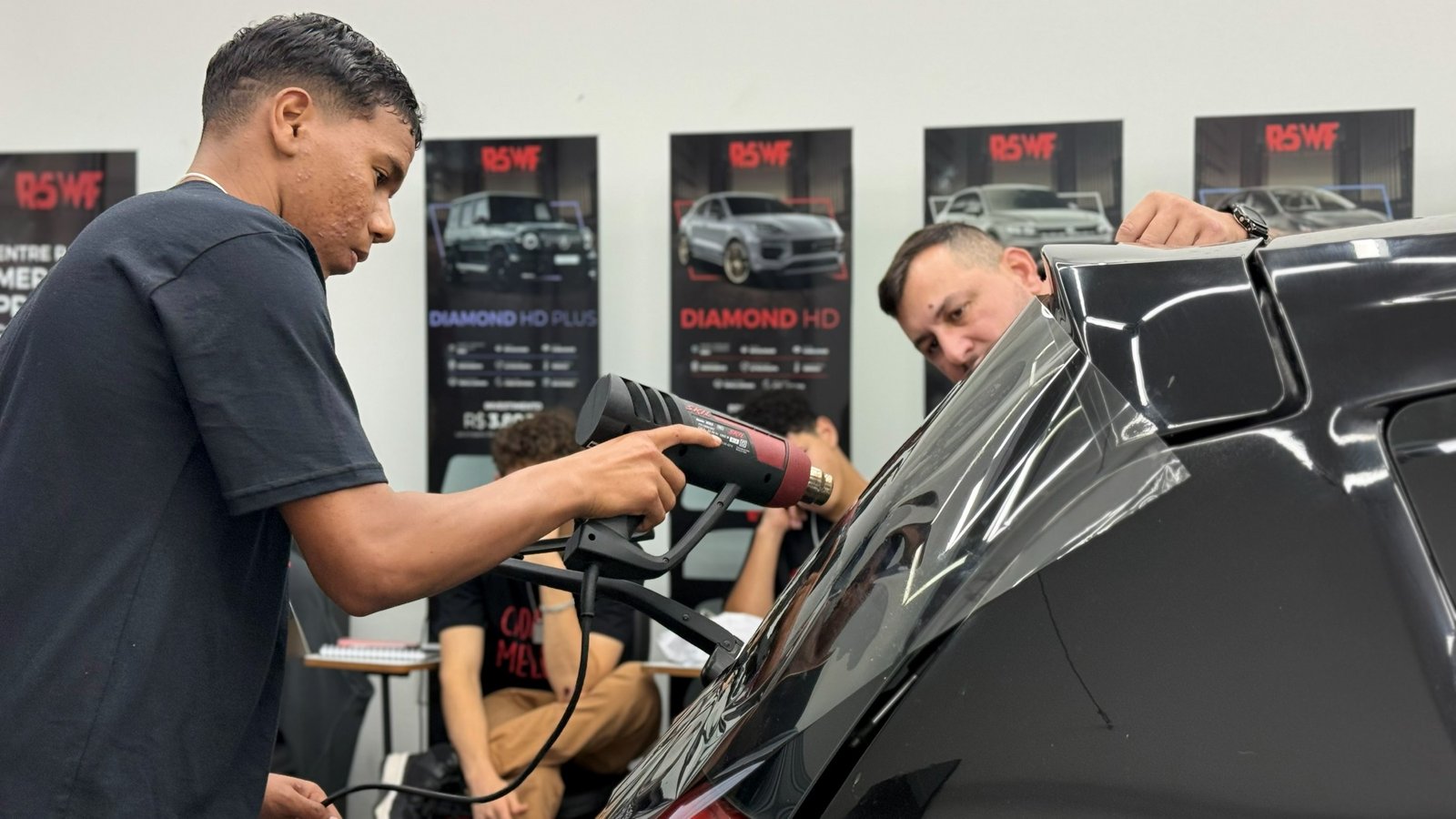 Aluno praticando a aplicação de película automotiva durante uma aula do Instituto GR5 Brasil